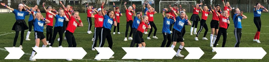 Jongens en meisjes dansend op een voetbalveld met blauwe en rode t-shirts