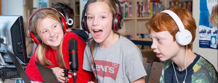 3 leerlingen voor een microfoon en hoofdtelefoon zang opnemen